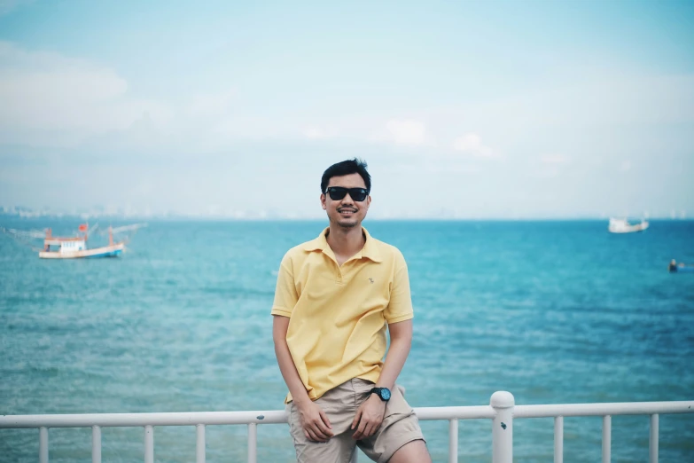 a man in yellow shirt standing next to the ocean