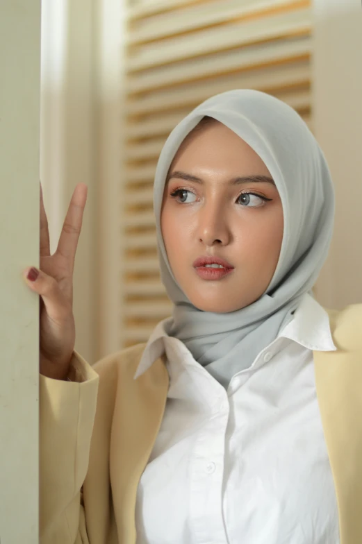 a woman wearing a hijab in front of a wall