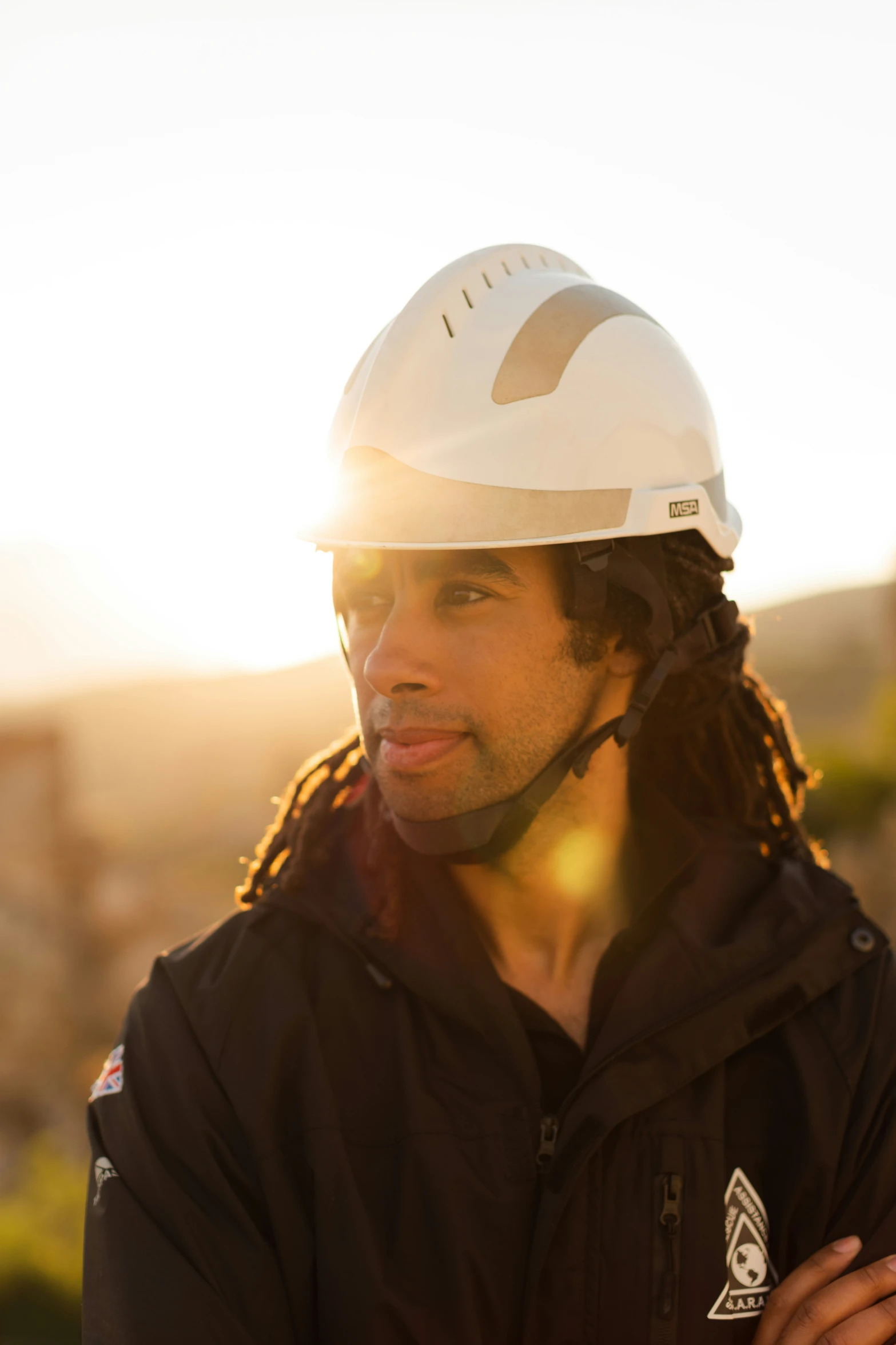 a man wearing a hard hat and jacket looking off into the distance