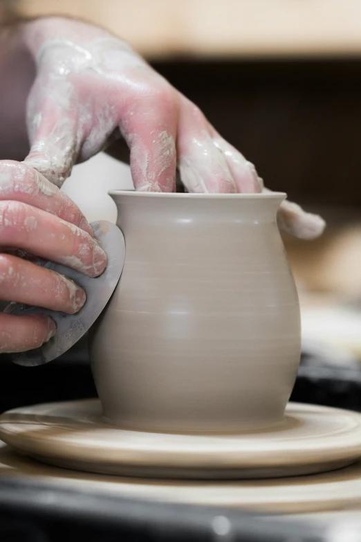 hands making pottery on a potter's wheel at work