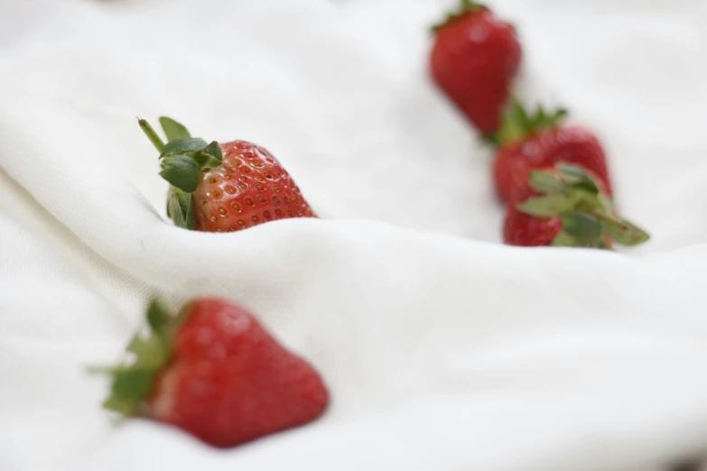 a group of red strawberries on white fabric