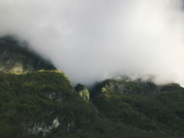 a mountain side with a cloud covering the top