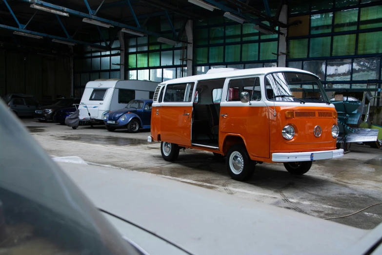 a vintage orange and white van is parked in an old warehouse