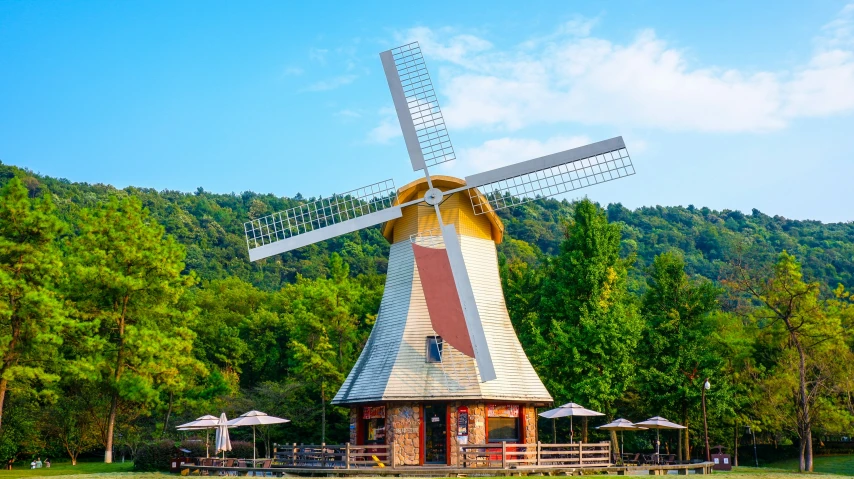 a windmill with tables and umbrellas in front