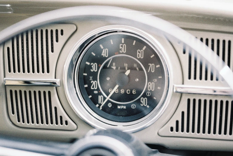 a clock on an old, white car's dashboard