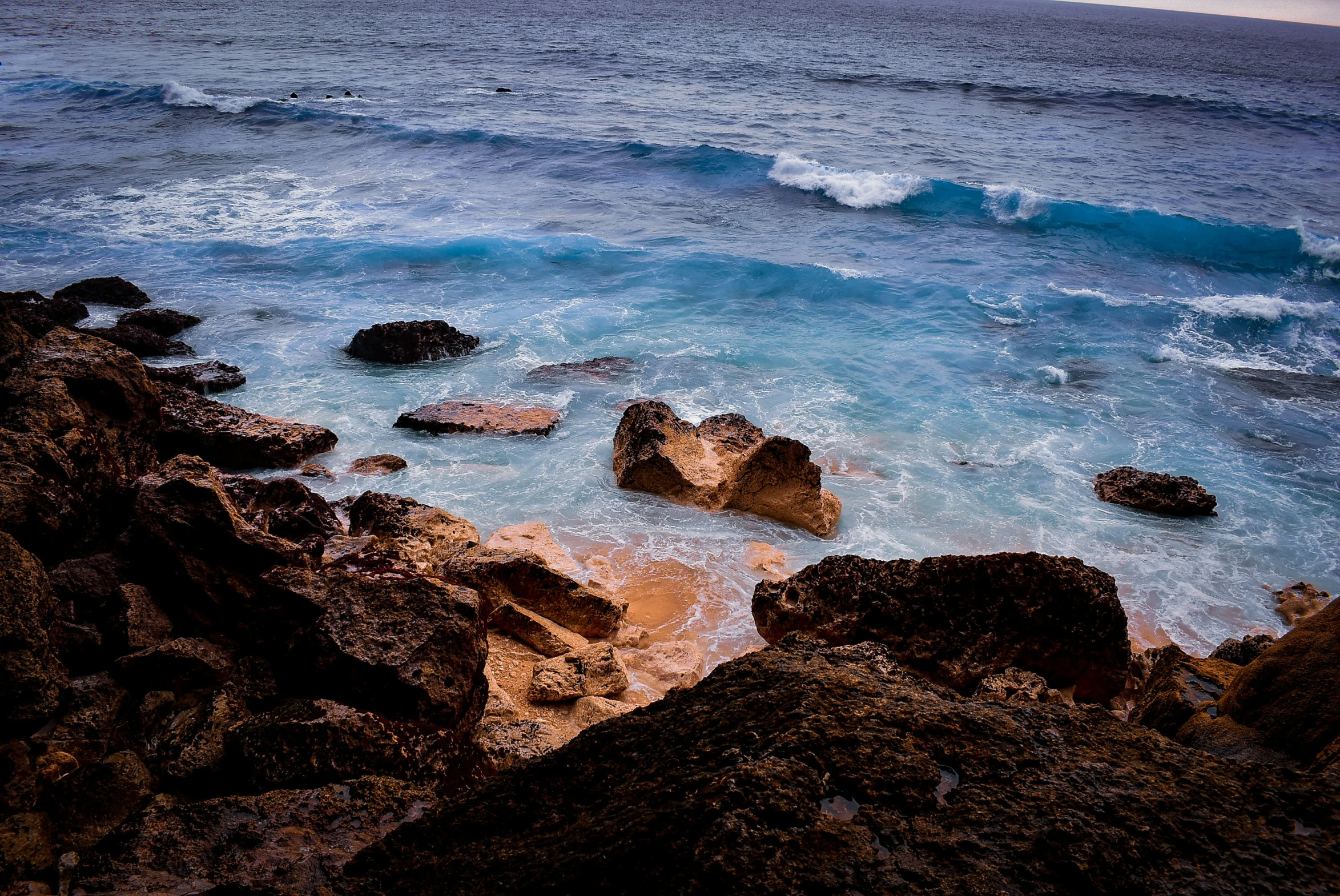 a wave crashes against the rocks and the shore