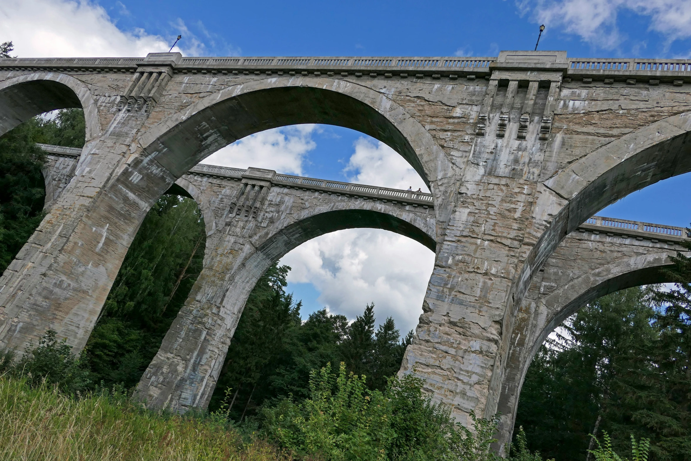 a very large stone bridge that is in the middle of some trees