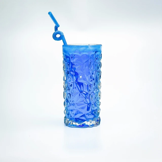 blue glass cup with handle sitting on white table