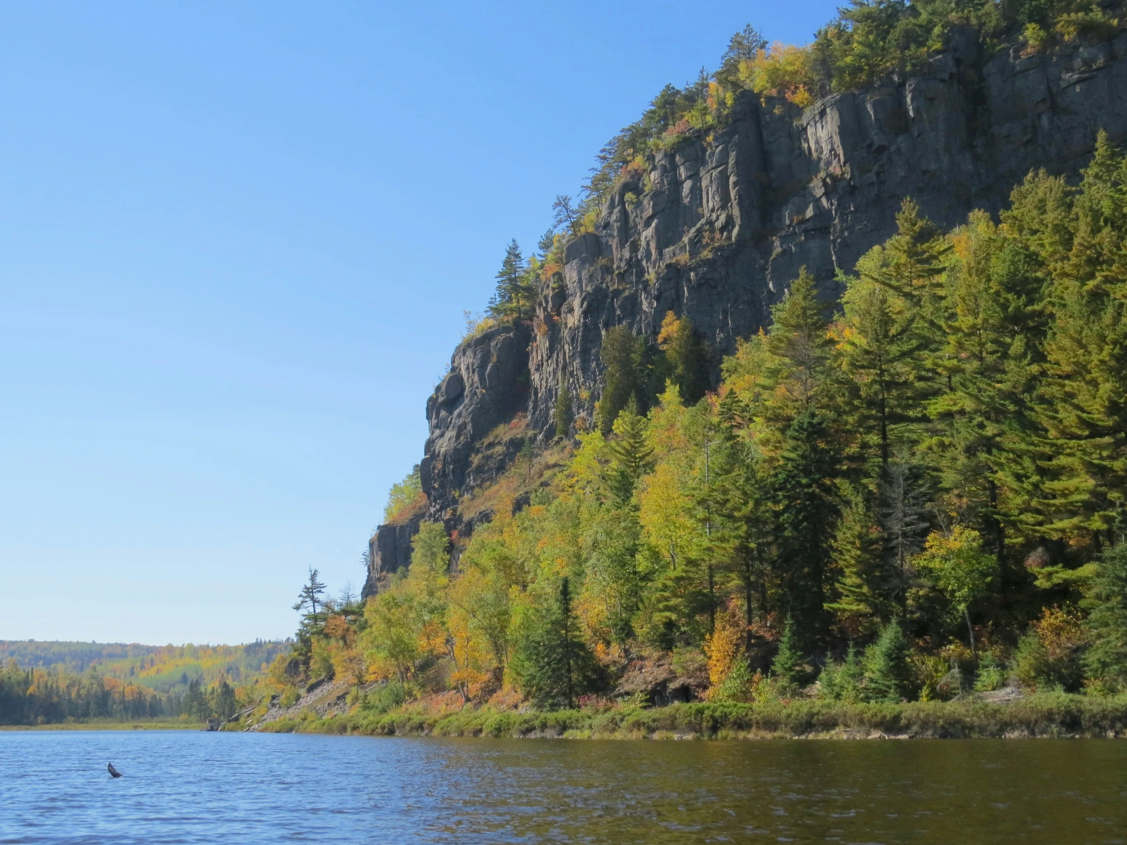 a lake with tall cliffs on either side, surrounded by colorful foliage