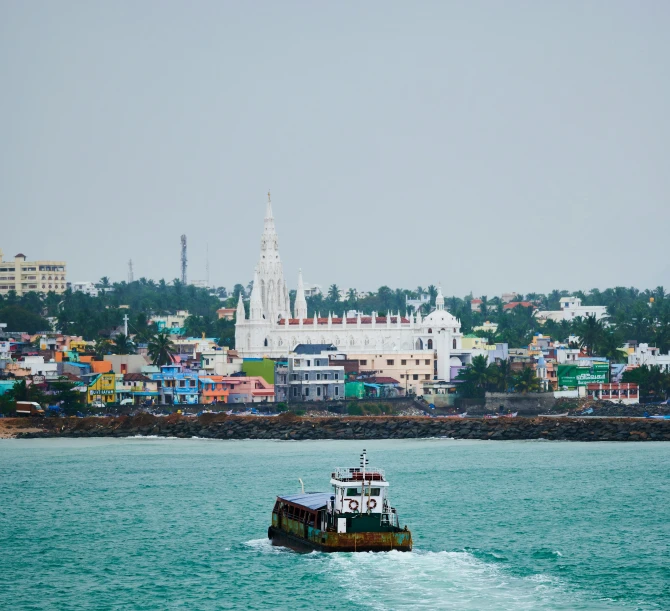 a tug boat on the ocean with buildings in the background