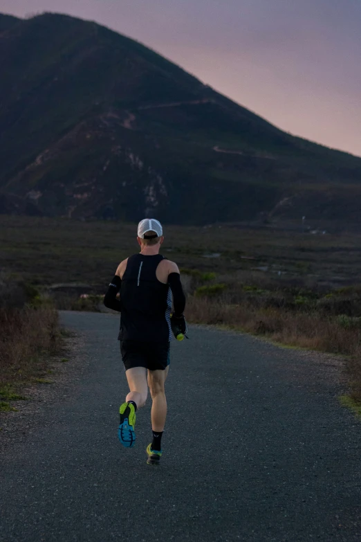 a man running down a road in front of a hill