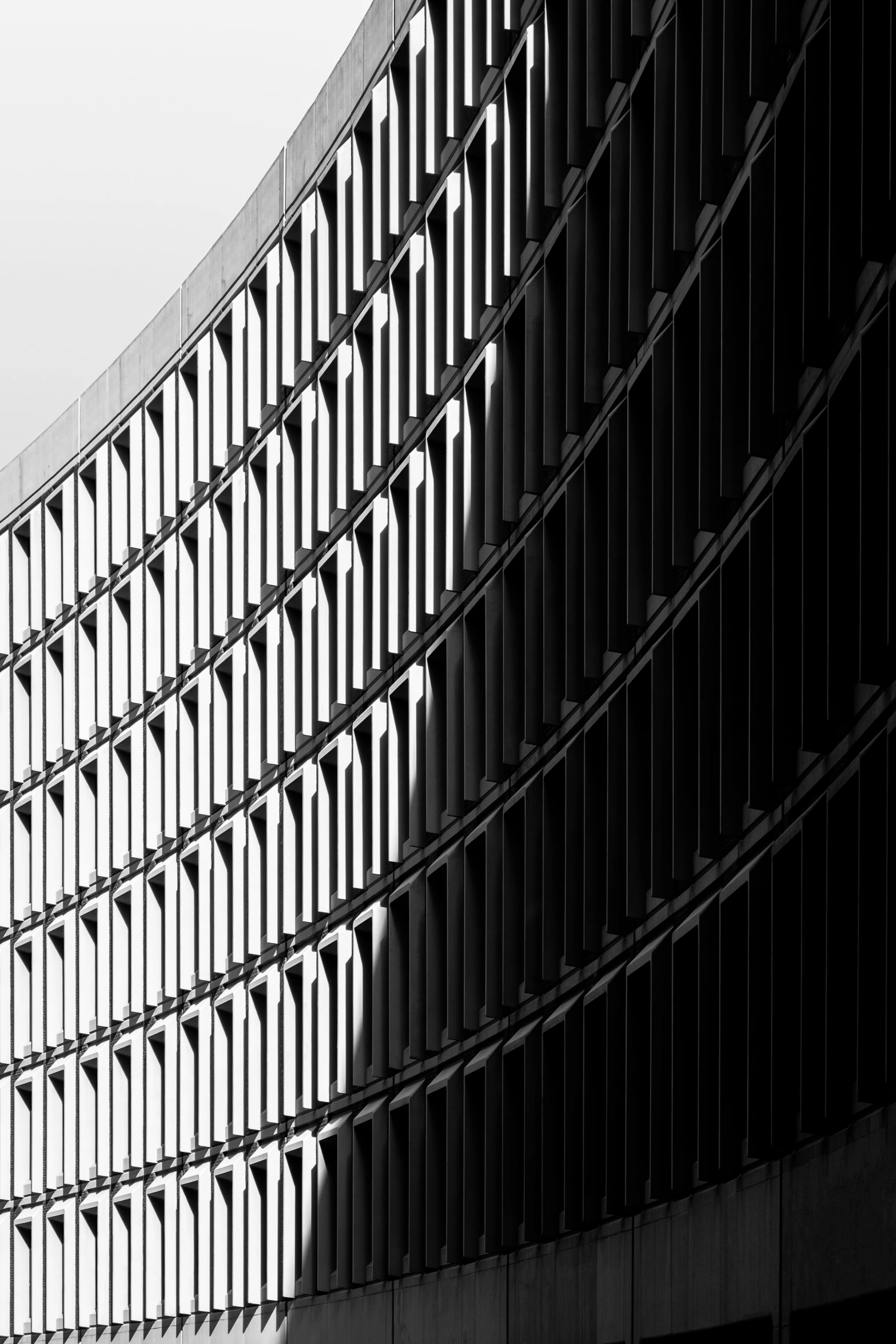 a tall black building with windows and a sky background