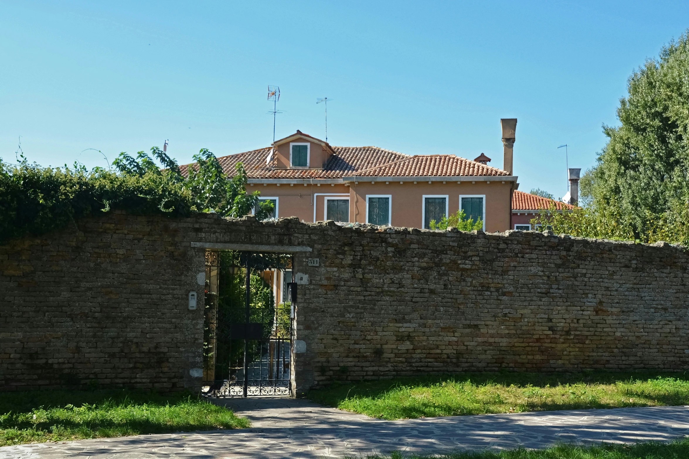 a house with an iron gate sitting in front of a stone wall