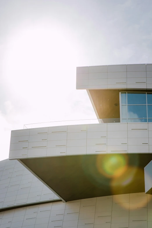 the back side of a building with a white roof and the sun shining in the windows