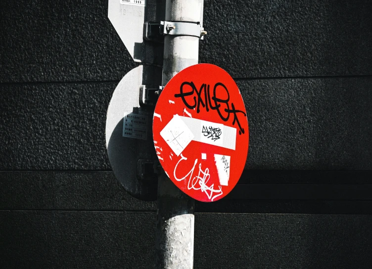 a street light covered in graffiti under a white traffic sign