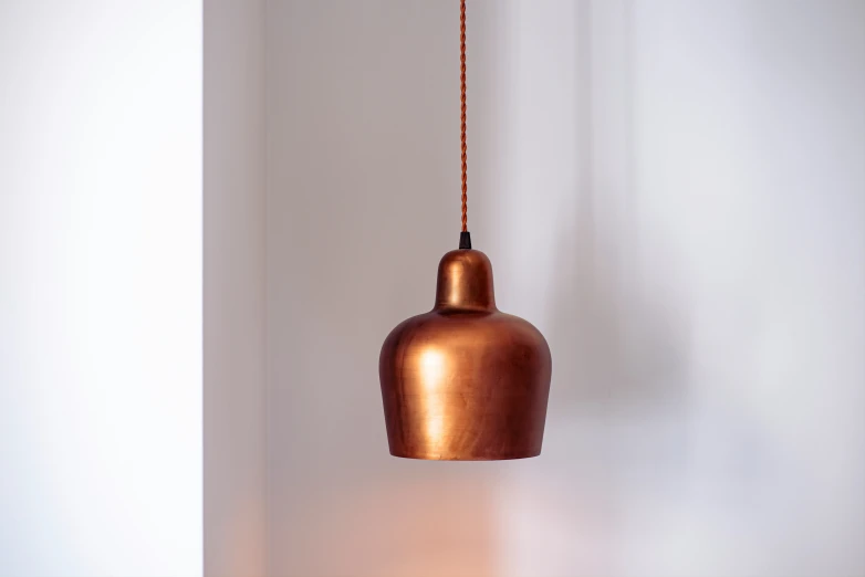 a hanging copper light fixture in a corner with white walls