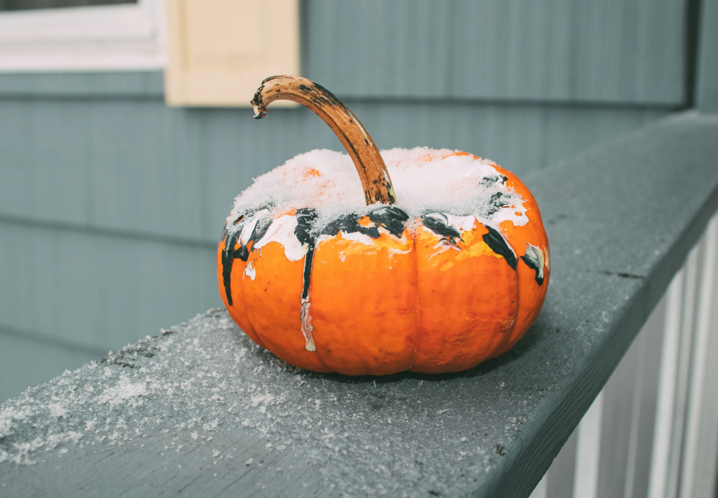 a small orange pumpkin sitting on the ledge of a building