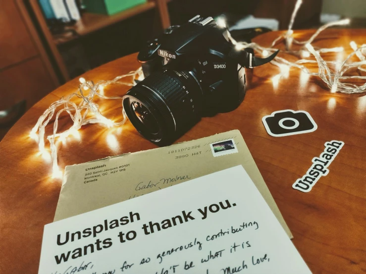 a pograph of a film camera next to a message, with string lights and an unopened camera in the background