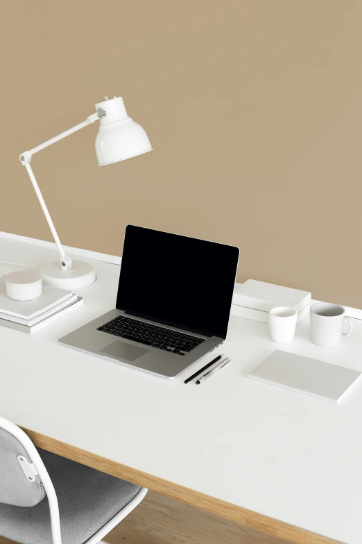 a white desk with a laptop on it and a lamp over it