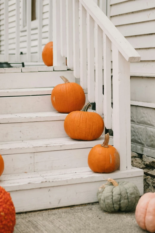 orange pumpkins sitting on the step of a house