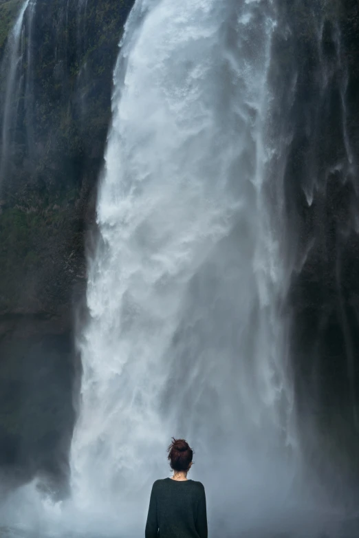 a woman standing in front of a very tall waterfall