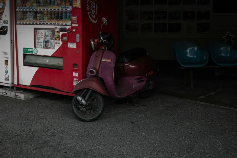 a vending machine and a moped sit next to each other