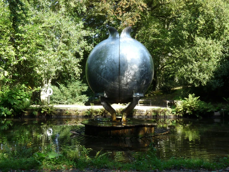 a water pond surrounded by trees next to a large metal vase