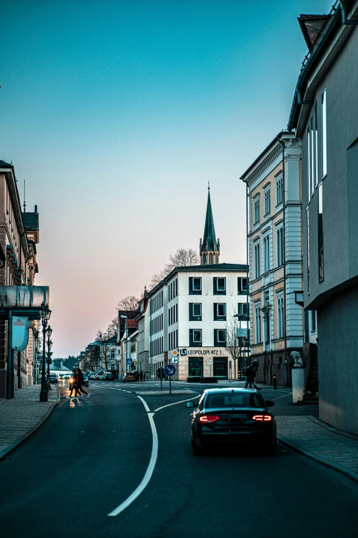 a small black car driving down a street