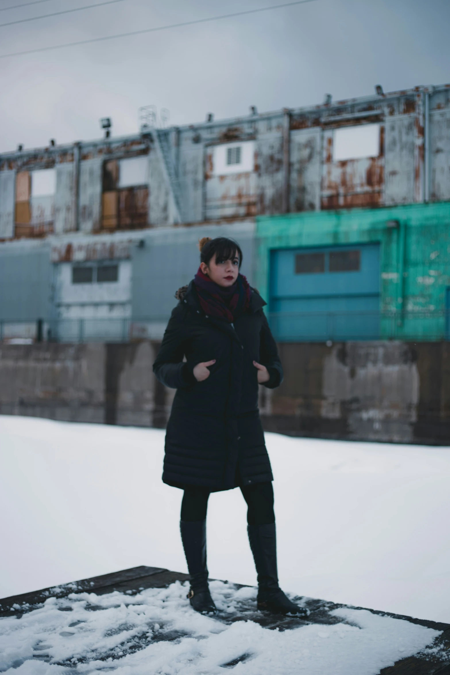 the woman is wearing black boots standing in the snow