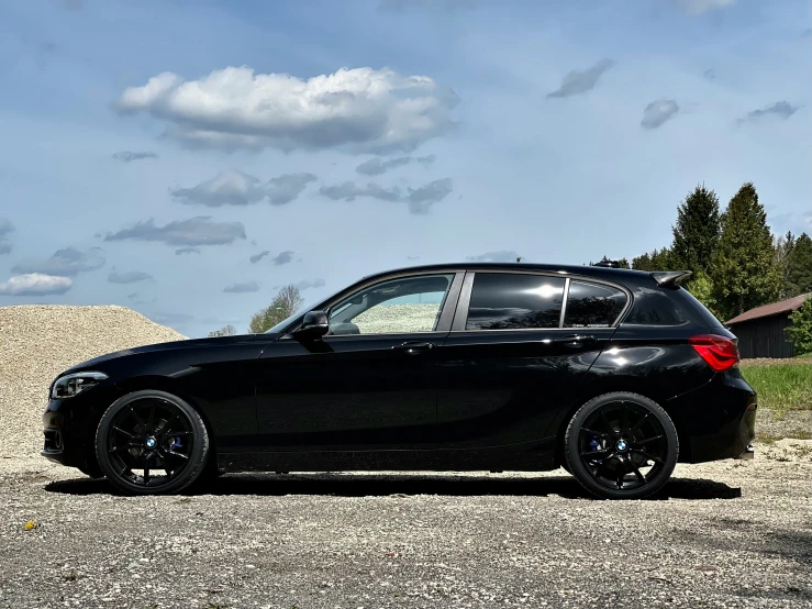 the bmw car is parked in the gravel