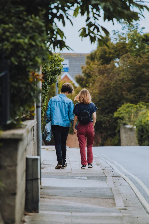 two people walking on the sidewalk carrying shopping bags