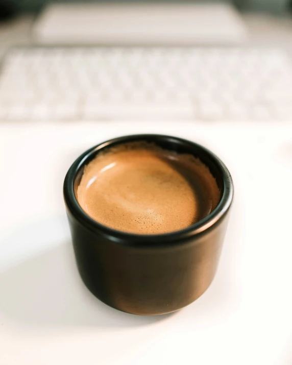 closeup of a small coffee cup in front of a computer