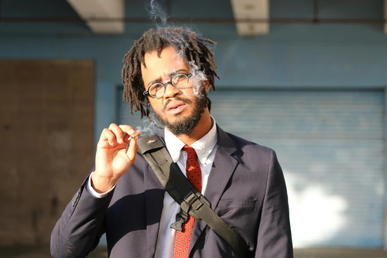 a man with dreadlocks holding out a cigarette