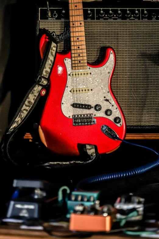 red guitar sitting on a table with an amp in background