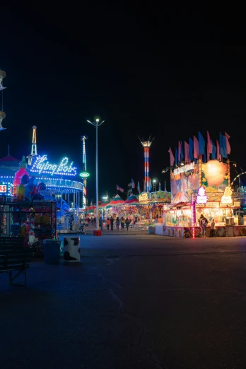 a carnival with booths and people walking around at night