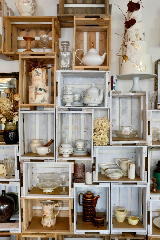 a shelf of white and brown dishes and other dishes in wooden crates