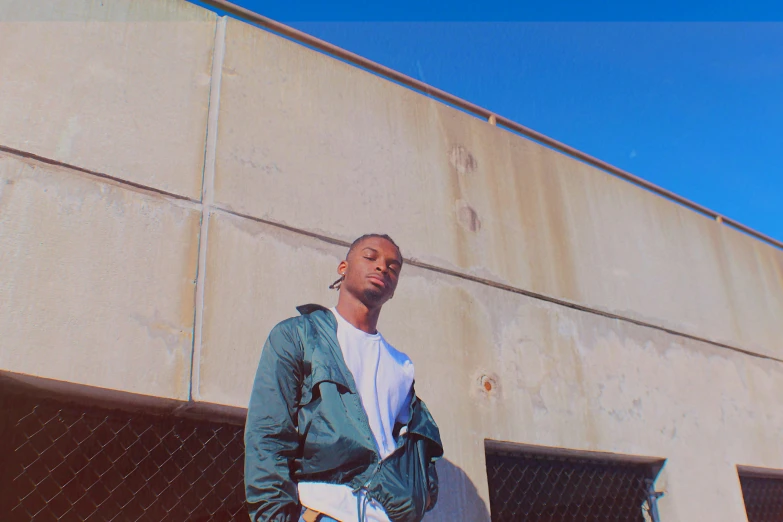 a man standing next to a fence wearing a jacket