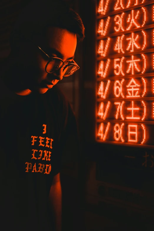 a man in glasses staring down while standing next to an information board