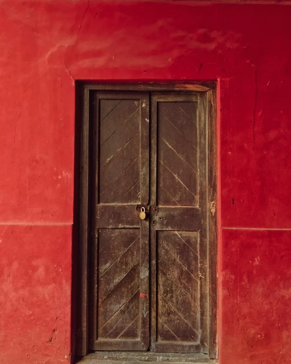 an old wooden door is in a red wall