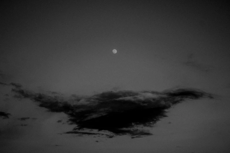 an eclipse in the sky with clouds and a half moon above