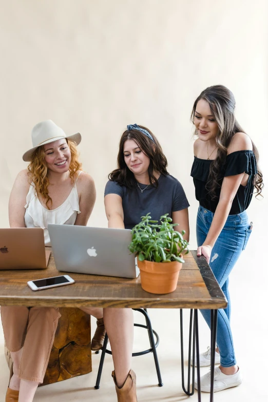 three girls sit at a desk with their computers