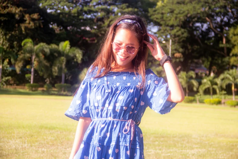 a young woman standing in the grass wearing a blue dress