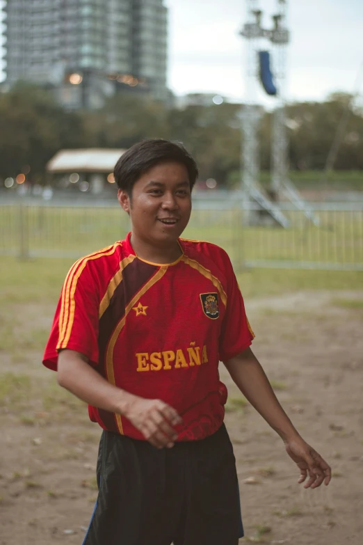 a  standing in front of a field holding a soccer ball