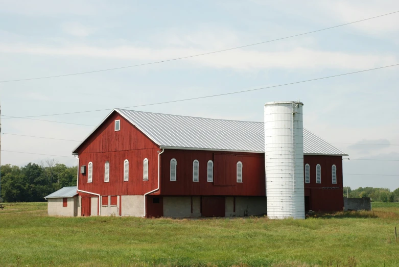 an old red barn and silo near a pole