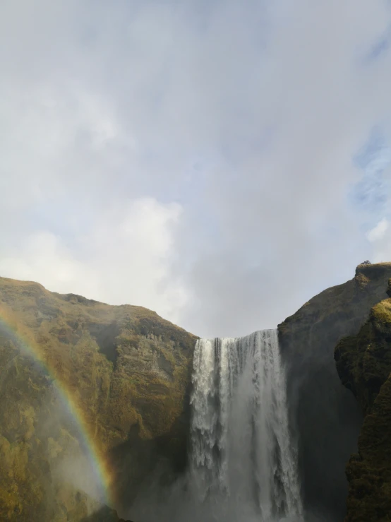 a rainbow over the falls in a mountain