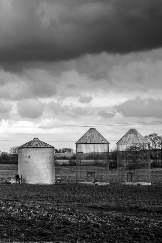 a farm with two silos sitting beside a large field