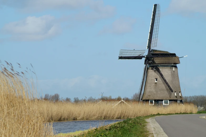 a windmill is standing in the grass next to a small lake