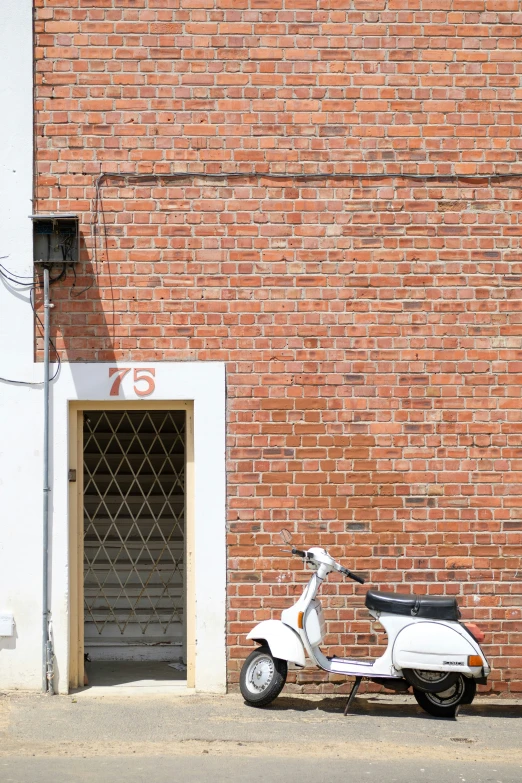 a white scooter sitting against a brick wall