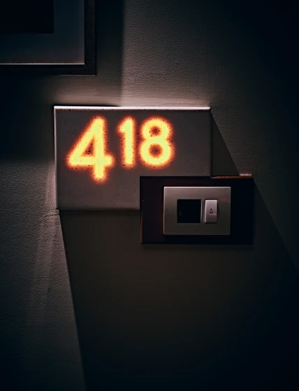 a black clock and a wall light in the corner