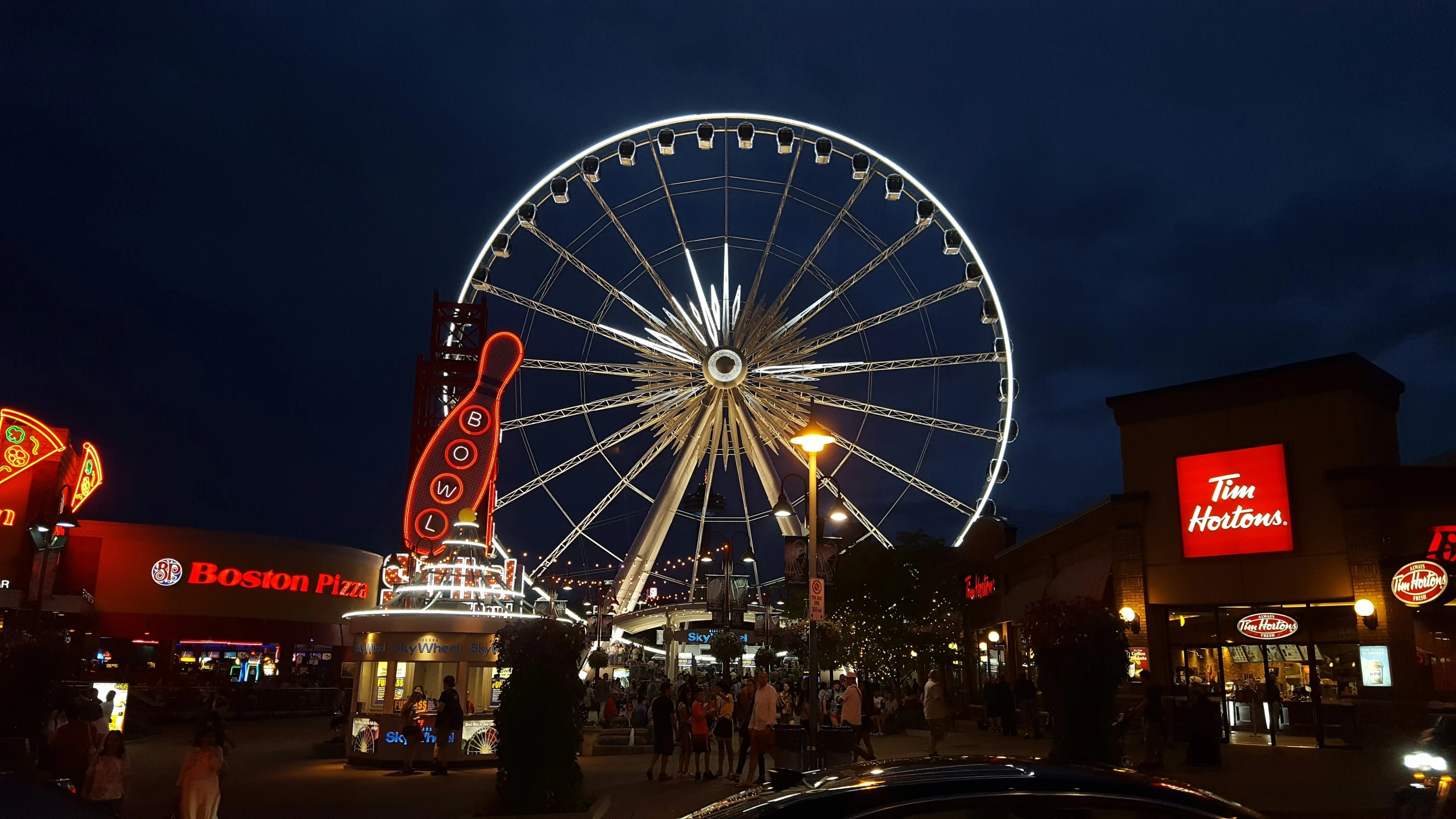 a ferris wheel at night in the center of a shopping district